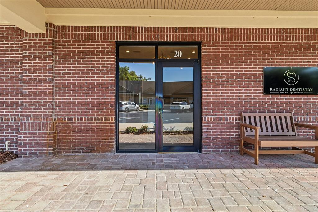 A brick building exterior features a glass door labeled 20 and a wooden bench — 13576 NW 2ND LANE UNIT 20, NEWBERRY, FL