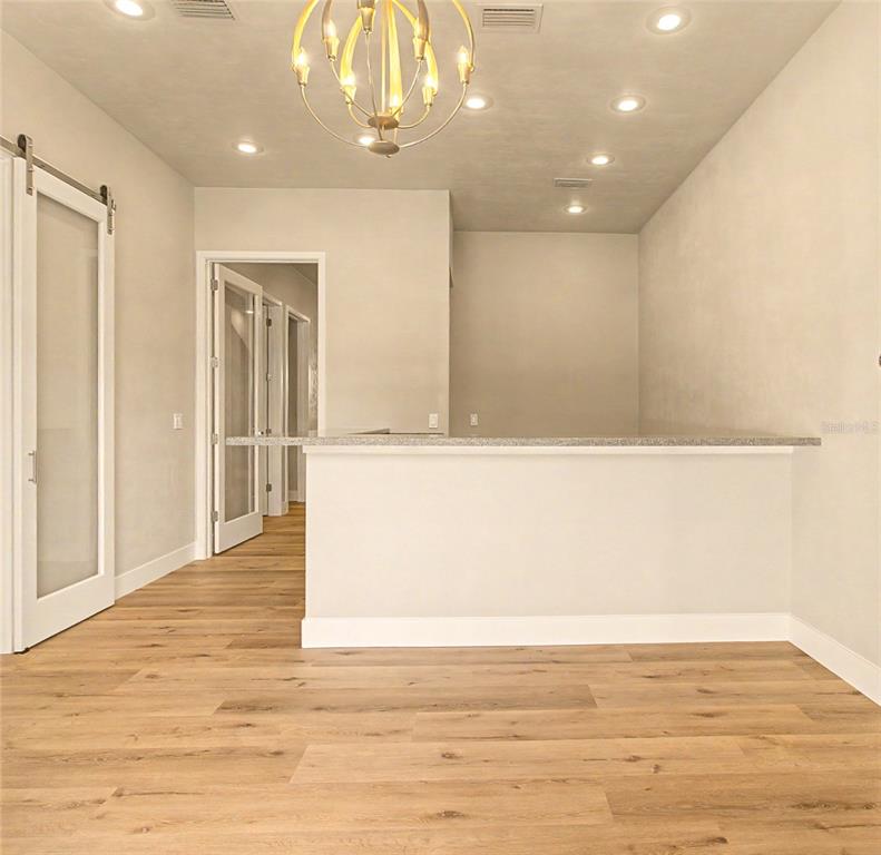 A room with light wood flooring, a breakfast bar, and a gold chandelier — 13576 NW 2ND LANE UNIT 20, NEWBERRY, FL