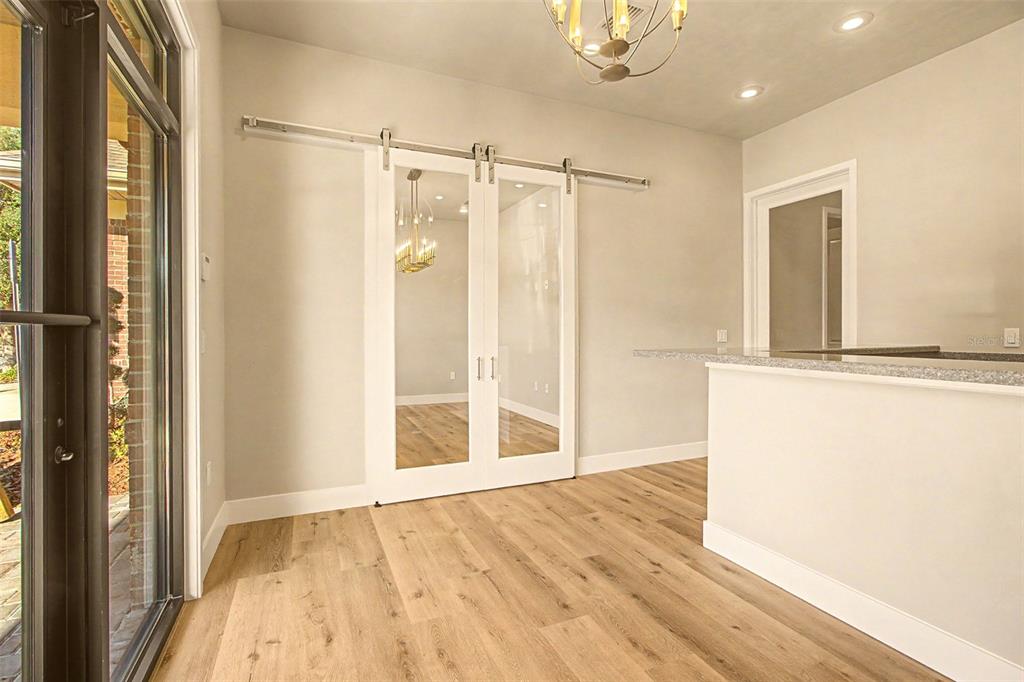 A room with light wood flooring, a granite-topped counter, and white sliding barn doors — 13576 NW 2ND LANE UNIT 20, NEWBERRY, FL