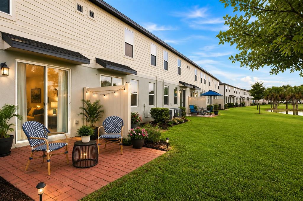A brick patio with two chairs and a small table sits outside a townhouse exterior — 2518 SWEET VIBURNUM WAY, OCOEE, FL