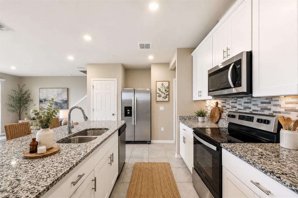 A kitchen features white cabinets, granite countertops, stainless steel appliances, and a central island — 2518 SWEET VIBURNUM WAY, OCOEE, FL