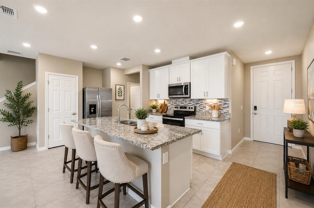 A kitchen with white cabinets, granite countertops, a center island with stools, and tile flooring — 2518 SWEET VIBURNUM WAY, OCOEE, FL