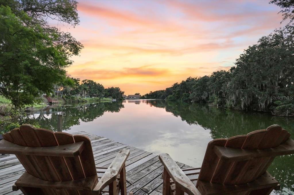 Two wooden chairs sit on a dock overlooking a calm lake at sunset — 448 LAKE HARRIS DRIVE, LAKELAND, FL