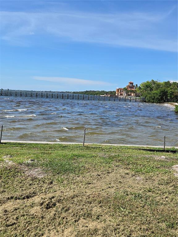 A long wooden pier extends into a choppy lake near a large house and trees — 333 N. SHORE DRIVE, SARASOTA, FL
