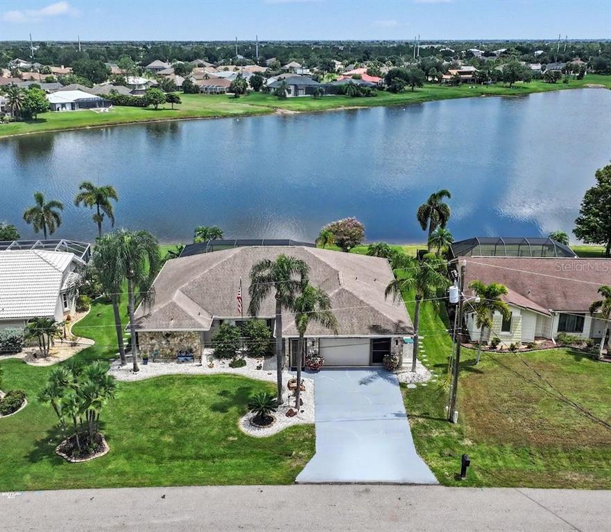 A single-story house with a stone facade, palm trees, and an American flag at sunset — 25426 SAINT HELENA LANE, PUNTA GORDA, FL