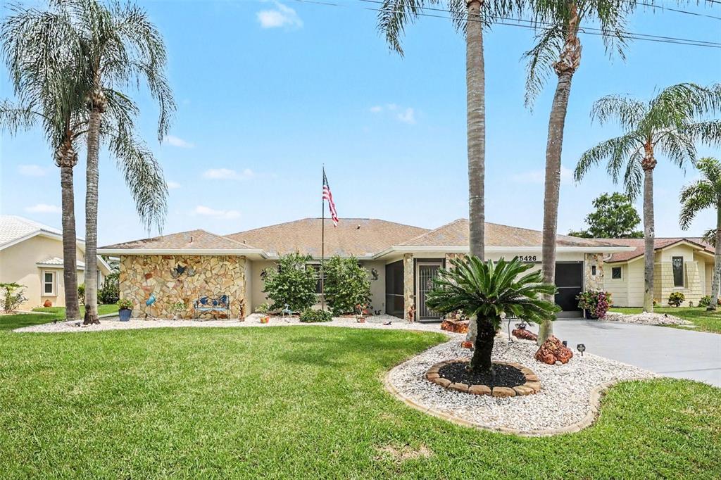 A single-story house with a two-car garage, palm trees, and a concrete driveway — 25426 SAINT HELENA LANE, PUNTA GORDA, FL