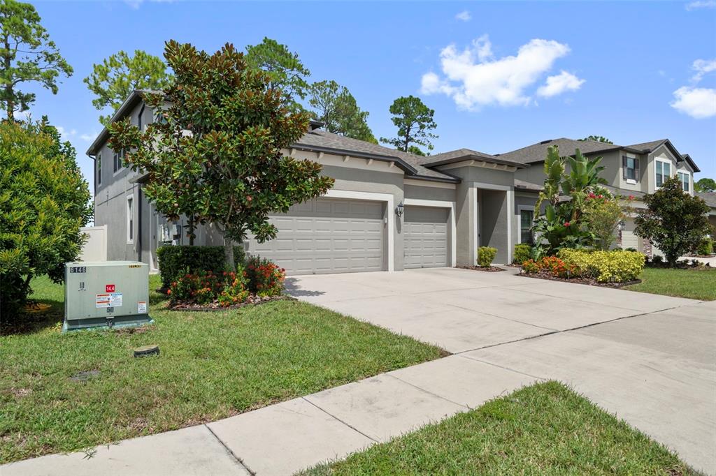 A two-story suburban house with a three-car garage and a concrete driveway — 18565 OBREGAN DRIVE, SPRING HILL, FL