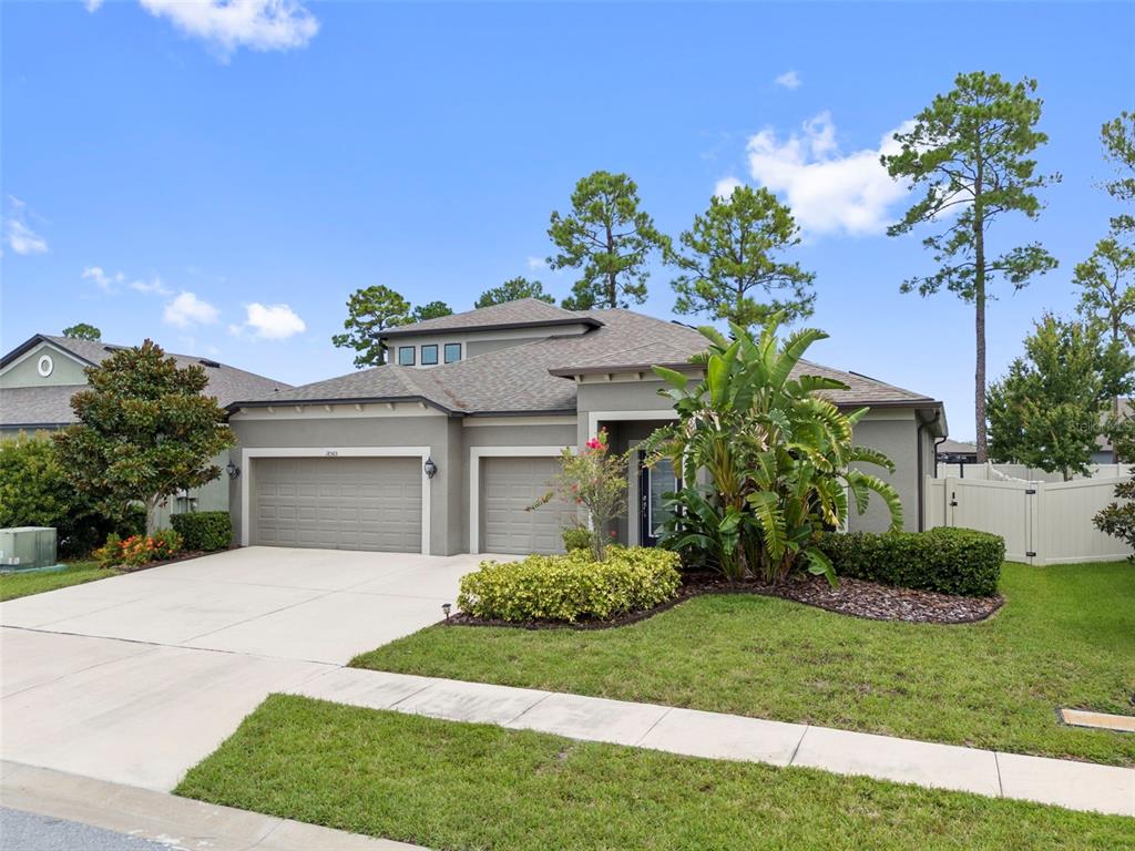 A single-story suburban house features a two-car garage, a landscaped front yard, and palm trees — 18565 OBREGAN DRIVE, SPRING HILL, FL