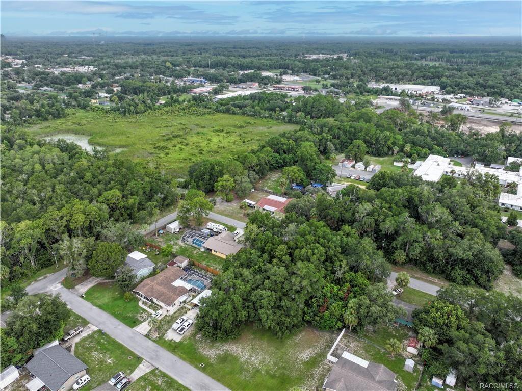 An aerial view shows several residential houses surrounded by dense trees and a large grassy field — 1134 NE 1ST TERRACE, CRYSTAL RIVER, FL
