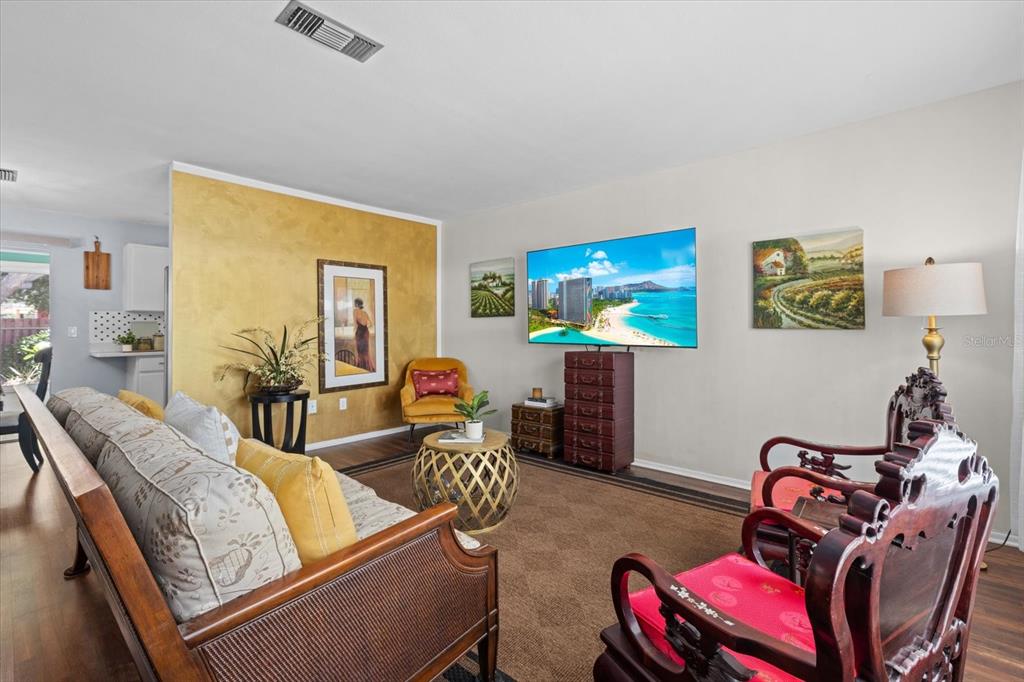A living room features a gold accent wall, a television, and traditional wooden furniture — 4305 CHINABERRY CIRCLE, BRADENTON, FL