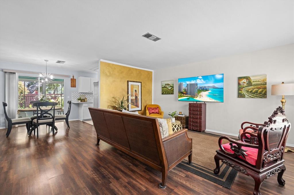 A living room with wood flooring, a sofa, a television, and an adjacent dining area — 4305 CHINABERRY CIRCLE, BRADENTON, FL