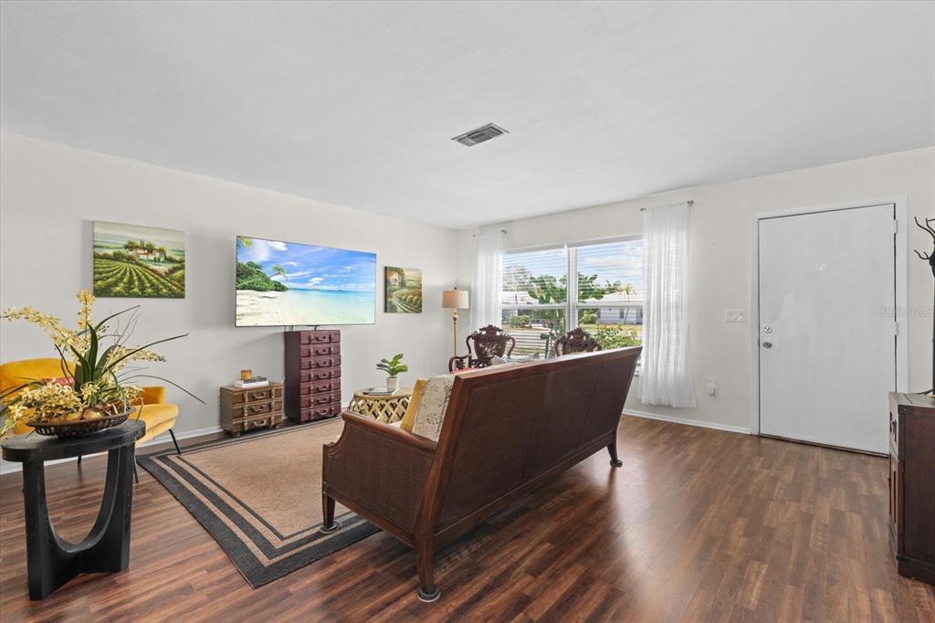 A living room features wood-look flooring, a wall-mounted television, and a dark wood sofa — 4305 CHINABERRY CIRCLE, BRADENTON, FL