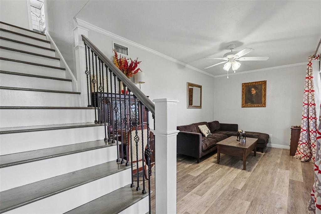 A living room with wood-look flooring, a sectional sofa, and a staircase with iron railings — 12321 82ND AVE, SEMINOLE, FL