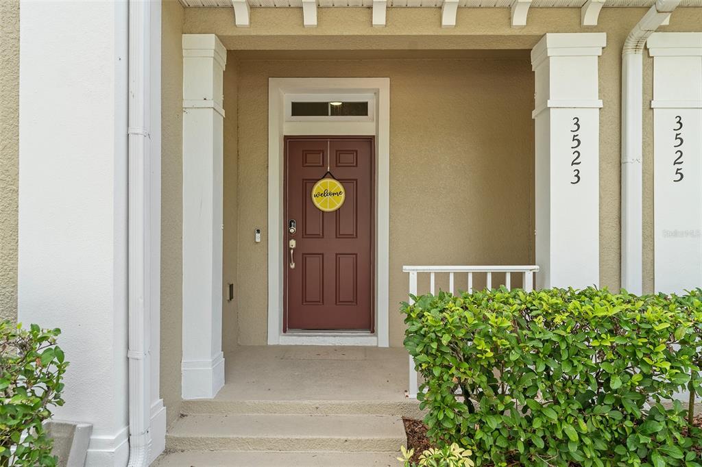 A brown front door with a lemon-shaped sign sits under a covered porch entrance — 3523 CLAY BRICK RD, ST CLOUD, FL