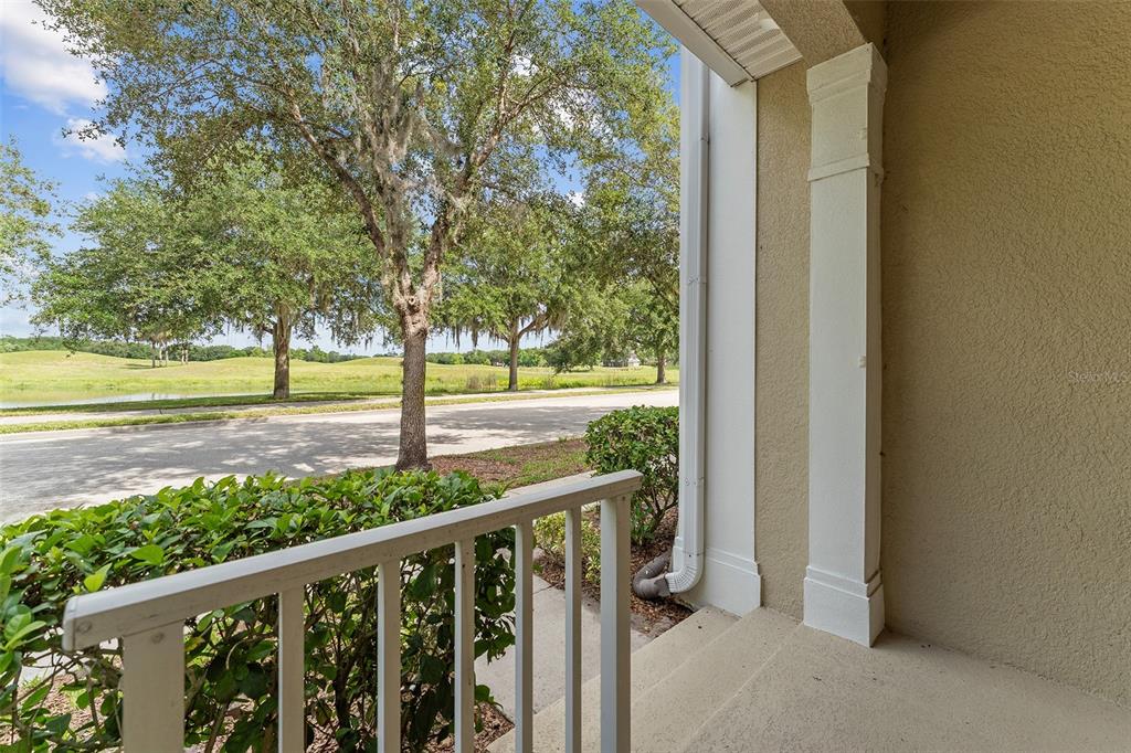 A view from a covered porch looking out toward a street, trees, and a pond — 3523 CLAY BRICK RD, ST CLOUD, FL