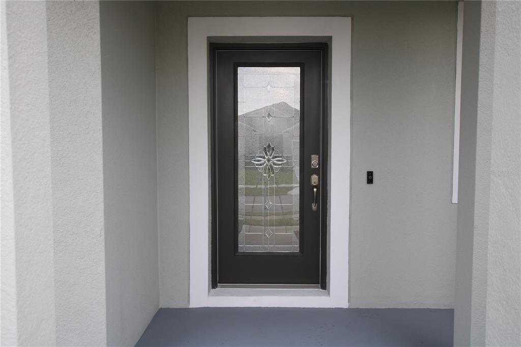 A dark front door with a decorative glass insert is set within a white frame — 516 INGLESIDE LANE, HAINES CITY, FL