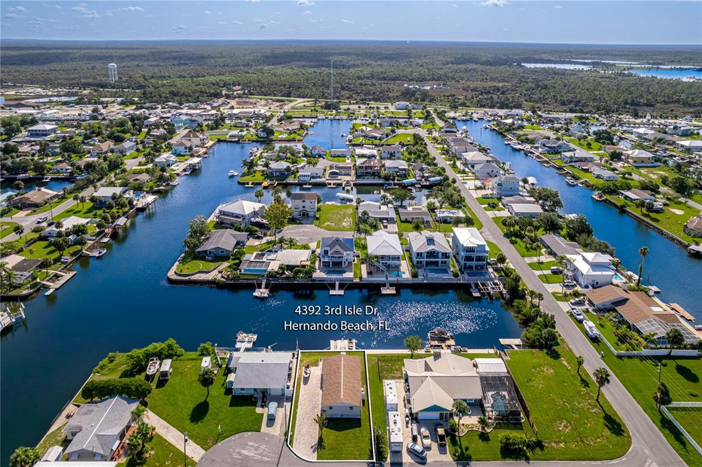 An aerial view shows a residential property with a house and lawn along a canal — 4392 3RD ISLE DRIVE, HERNANDO BEACH, FL