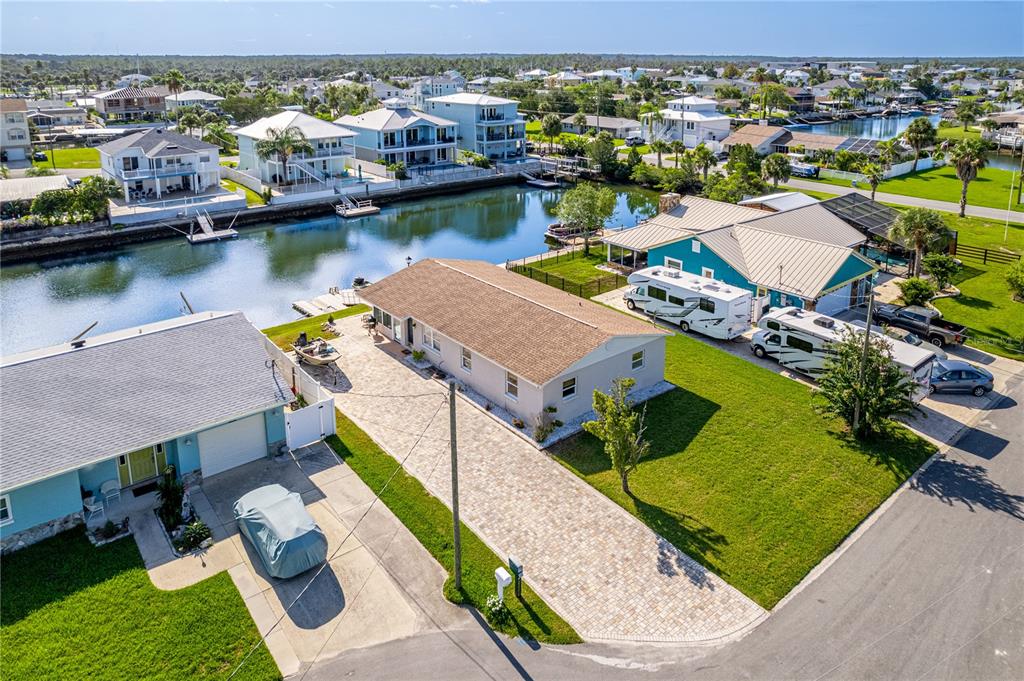An aerial view shows a residential street with houses, a canal, and parked vehicles — 4392 3RD ISLE DRIVE, HERNANDO BEACH, FL