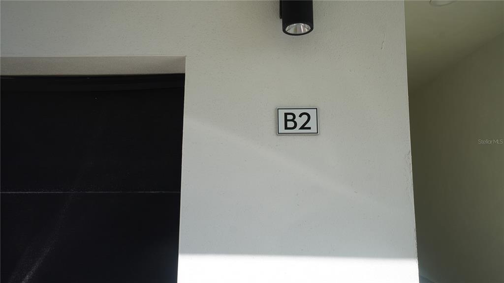A black door is adjacent to a white wall featuring a B2 unit number sign — 15405 GULF BOULEVARD UNIT B2, MADEIRA BEACH, FL