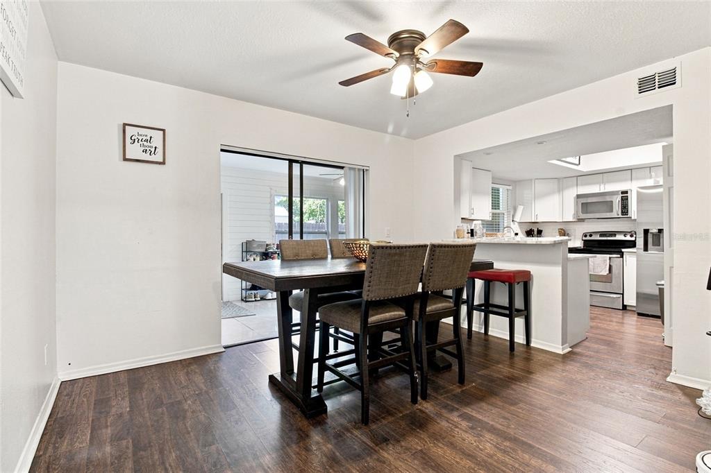 A dining area with a wooden table and chairs sits adjacent to a white kitchen — 3039 ABBEY COURT, CLEARWATER, FL