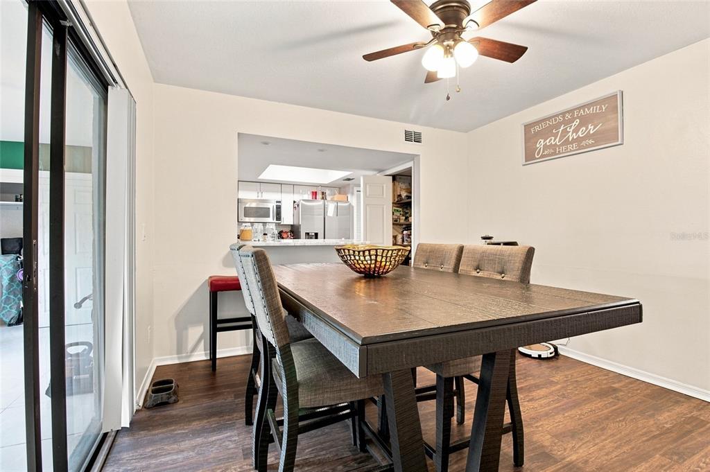 A dining room features a wooden table, upholstered chairs, a ceiling fan, and wall decor — 3039 ABBEY COURT, CLEARWATER, FL