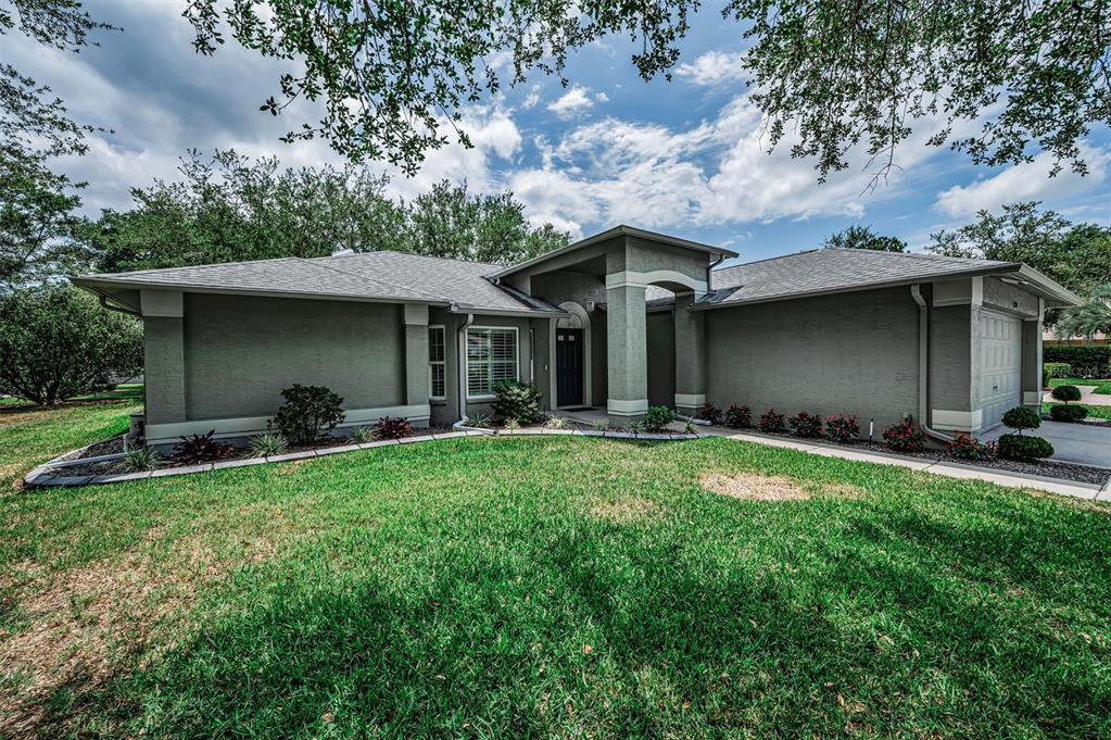 A single-story gray house with a covered entryway and a large front lawn — 1300 FALLOWFIELD DRIVE, TRINITY, FL