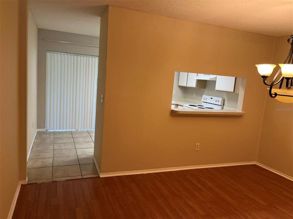 A dining area with wood-look flooring features a pass-through window looking into the kitchen — 2030 FLUORSHIRE DRIVE, BRANDON, FL