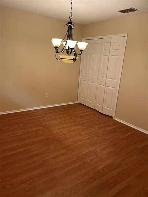 A room with wood-look flooring, beige walls, a chandelier, and white bi-fold closet doors — 2030 FLUORSHIRE DRIVE, BRANDON, FL
