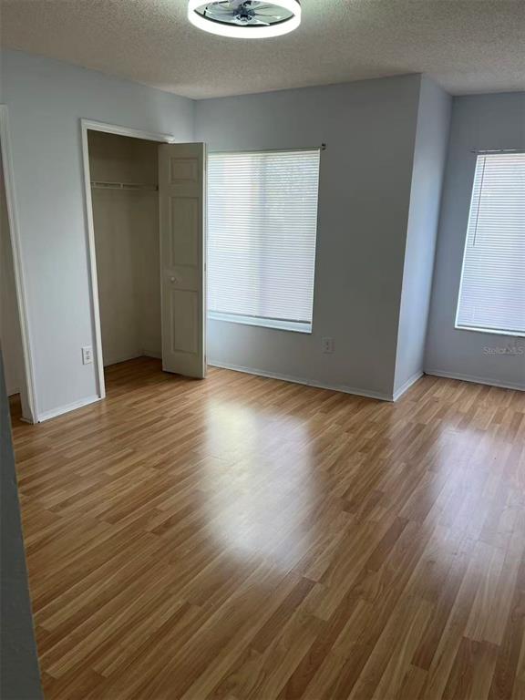 An empty bedroom features light-colored walls, wood-look flooring, a closet, and two windows with blinds — 2030 FLUORSHIRE DRIVE, BRANDON, FL