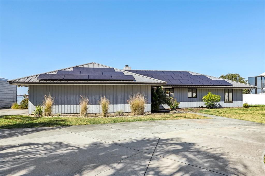 A single-story house with a metal roof and solar panels sits behind a concrete driveway — 3050 CRUMP ROAD, WINTER HAVEN, FL