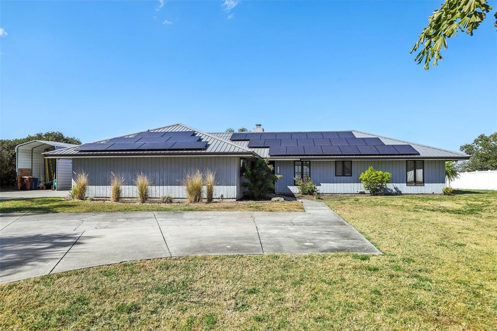 A single-story house with a metal roof, solar panels, and a concrete driveway — 3050 CRUMP ROAD, WINTER HAVEN, FL