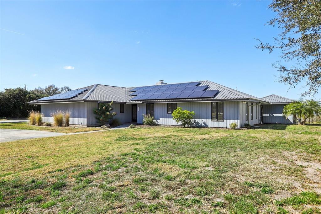 A single-story house with gray vertical siding and solar panels on a metal roof — 3050 CRUMP ROAD, WINTER HAVEN, FL