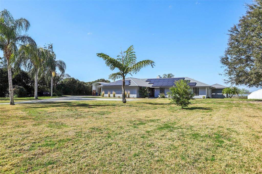 A single-story house with solar panels on the roof sits on a large grassy lot — 3050 CRUMP ROAD, WINTER HAVEN, FL