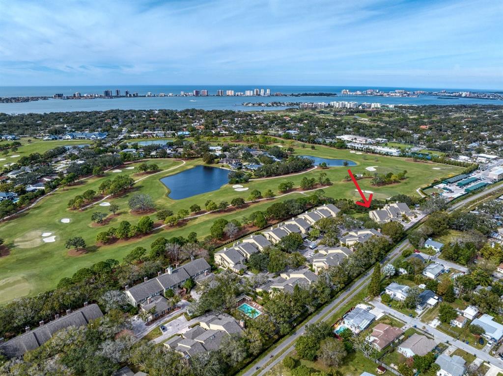 An aerial view shows a residential complex adjacent to a golf course and water — 75 PELICAN PLACE, BELLEAIR, FL