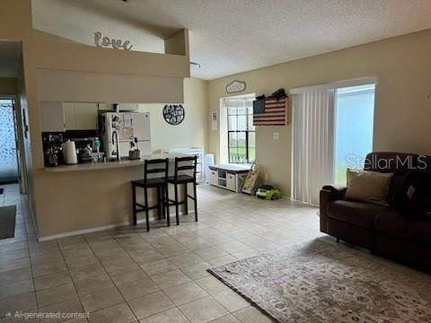 An open-concept living room and kitchen area with tile flooring and a breakfast bar — 516 SHERIDAN DRIVE, PALM HARBOR, FL