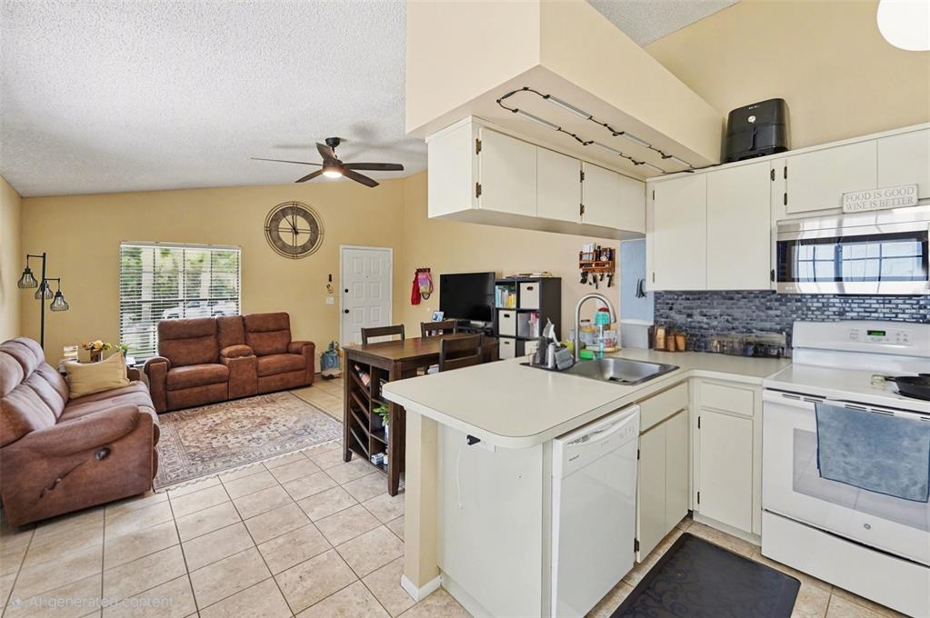 An open-concept living area features a kitchen with white cabinets and a connected living room — 516 SHERIDAN DRIVE, PALM HARBOR, FL