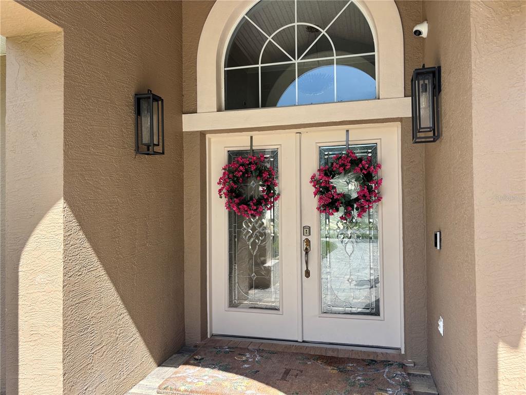 A front entrance features double glass-paneled doors with floral wreaths under an arched transom window — 1701 TIMBER EDGE DRIVE, DELAND, FL