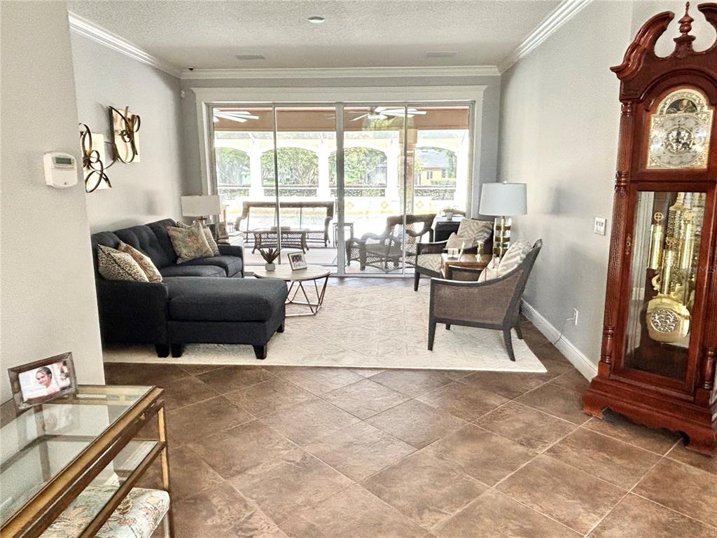 A living room features tile flooring, a dark sectional sofa, and a tall grandfather clock — 1701 TIMBER EDGE DRIVE, DELAND, FL