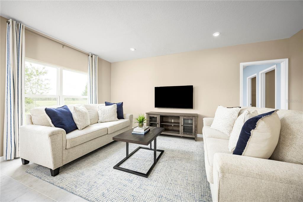 A living room features two beige sofas, a coffee table, a TV console, and windows — 11448 SE 77TH AVENUE, BELLEVIEW, FL