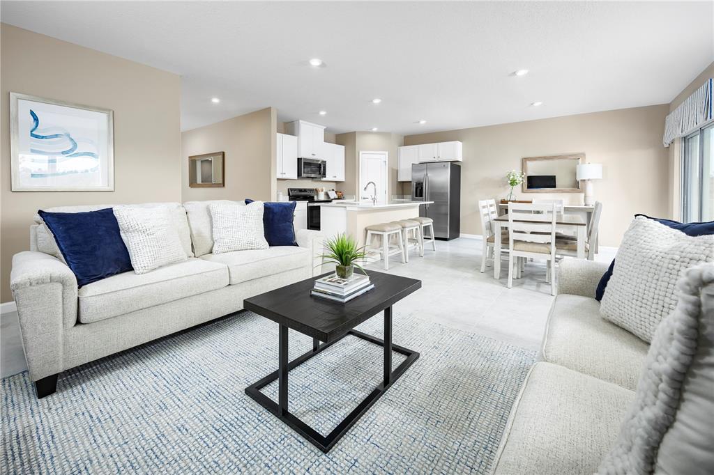 An open-concept living room and kitchen feature light-colored sofas, a dark coffee table, and tile flooring — 11448 SE 77TH AVENUE, BELLEVIEW, FL