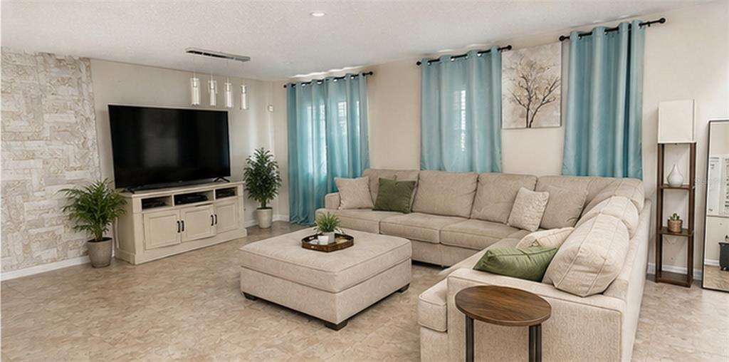 A living room features a large sectional sofa, a television console, and light-colored tile flooring — 528 STONEWALL AVENUE, HAINES CITY, FL