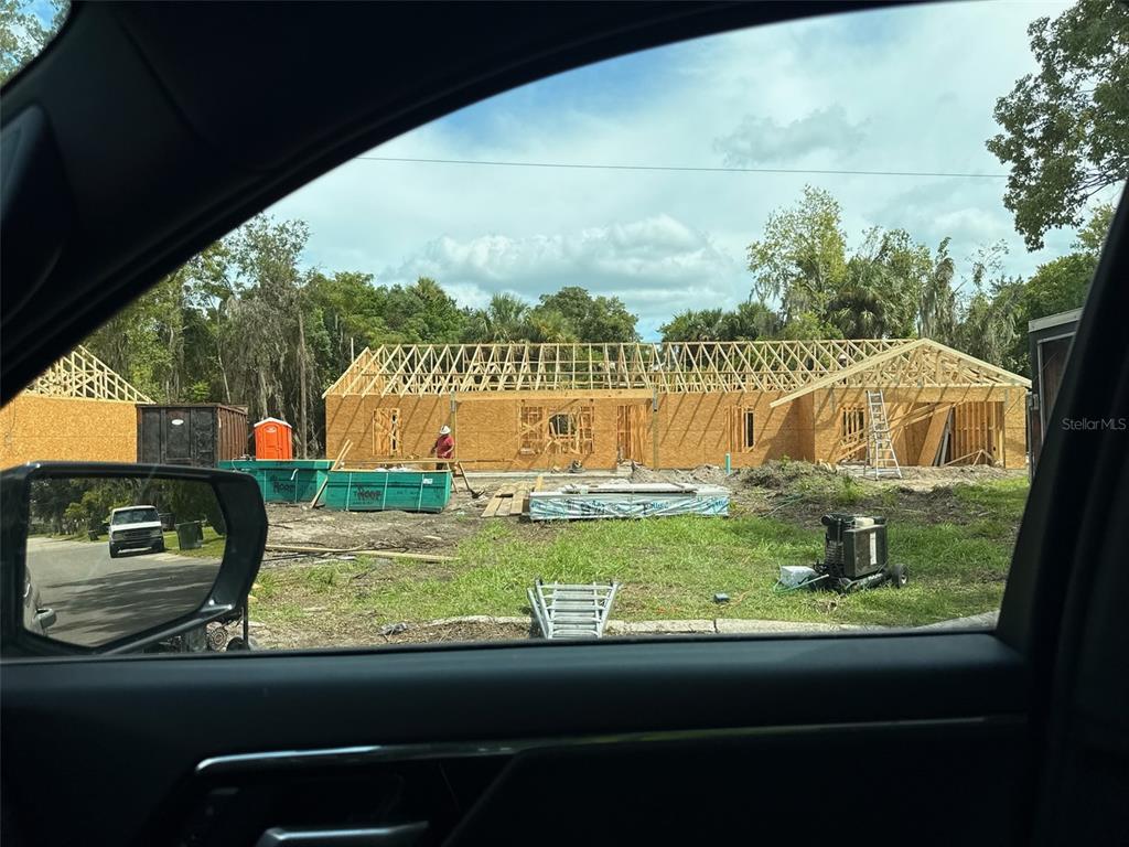 A construction site shows a wooden house frame with roof trusses under a cloudy sky — 101 YAWN AVENUE, INTERLACHEN, FL