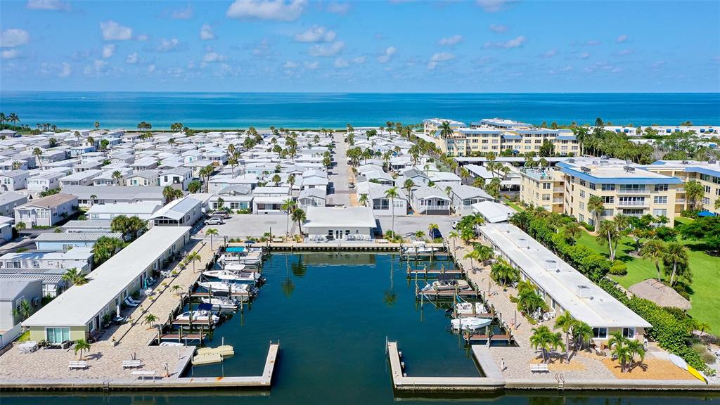 An aerial view shows a marina with docked boats surrounded by residential buildings and palm trees — 36 TWIN SHORES BOULEVARD, LONGBOAT KEY, FL