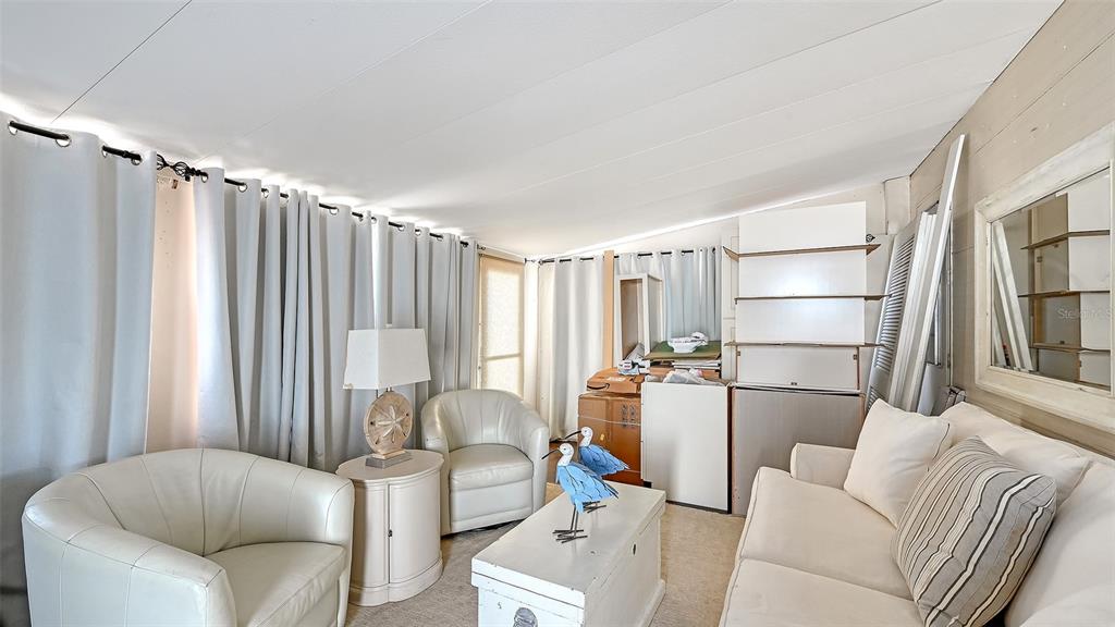 A sunroom features white furniture, light-colored curtains, a coffee table, and a white sofa — 36 TWIN SHORES BOULEVARD, LONGBOAT KEY, FL