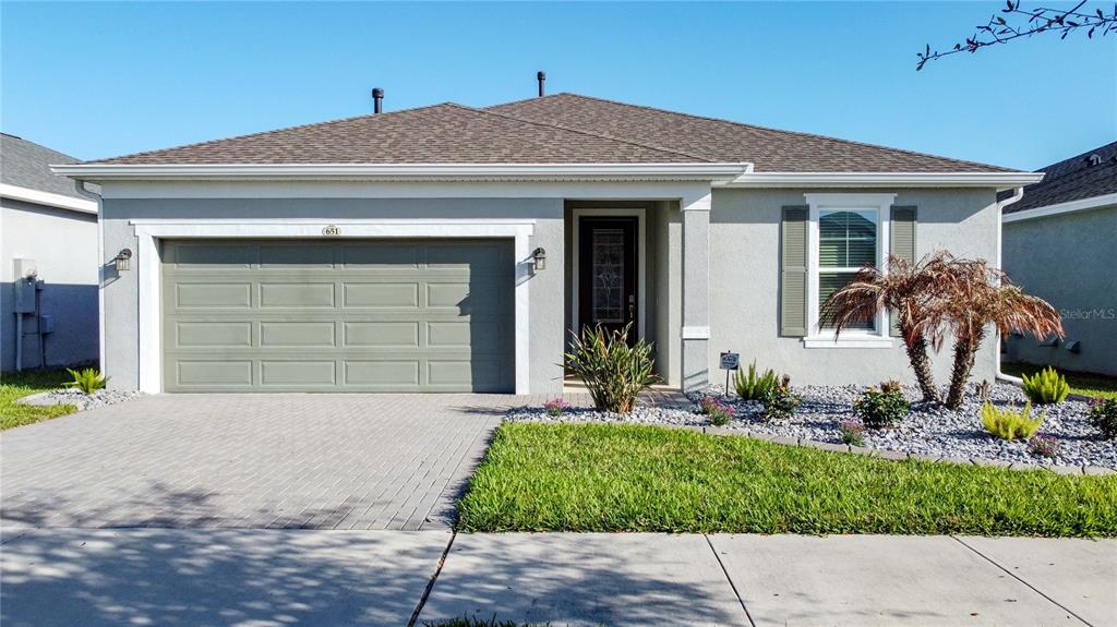 A single-story house with a gray stucco exterior, a two-car garage, and a landscaped yard — 651 CONSERVATION BOULEVARD, GROVELAND, FL