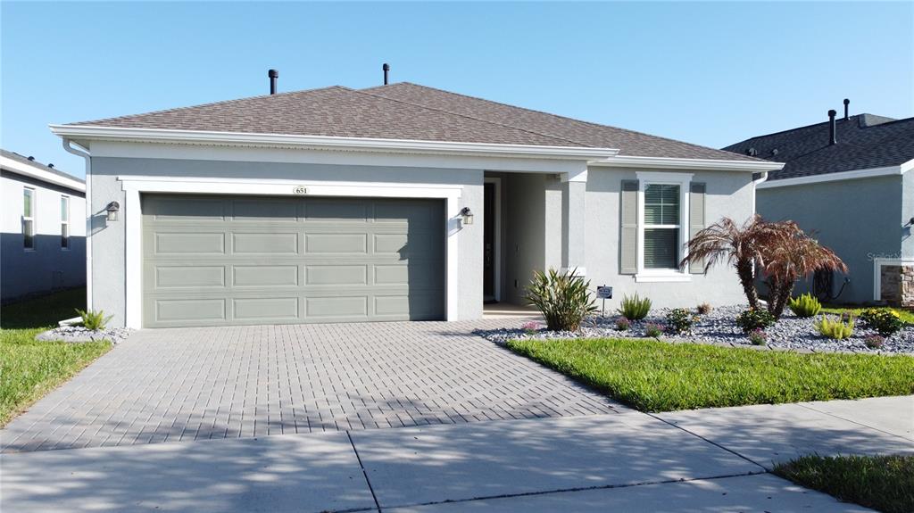 A single-story house with a gray stucco exterior, a two-car garage, and a paved driveway — 651 CONSERVATION BOULEVARD, GROVELAND, FL