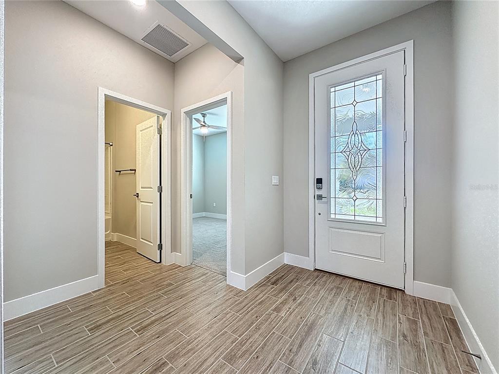 An entryway with wood-look tile flooring, a glass-paneled front door, and two interior doorways — 651 CONSERVATION BOULEVARD, GROVELAND, FL