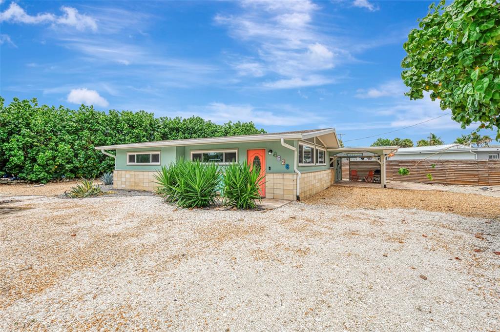 A single-story house with a light green exterior, stone accents, and a gravel driveway — 4626 GLEASON AVENUE, SARASOTA, FL
