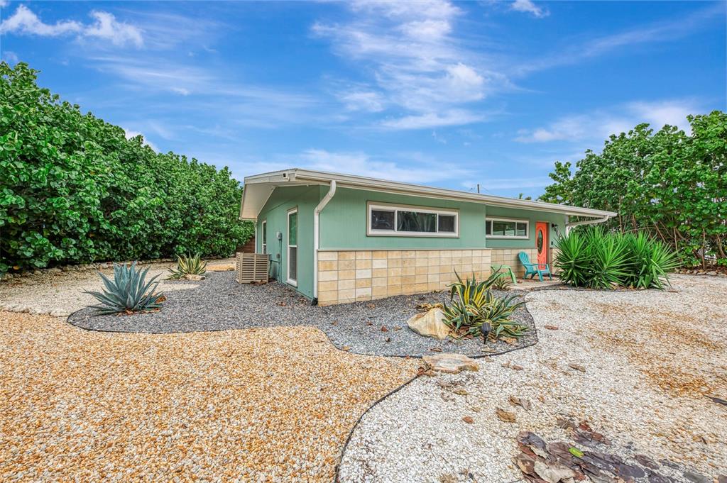 A single-story house with green siding and stone accents sits on a gravel lot — 4626 GLEASON AVENUE, SARASOTA, FL