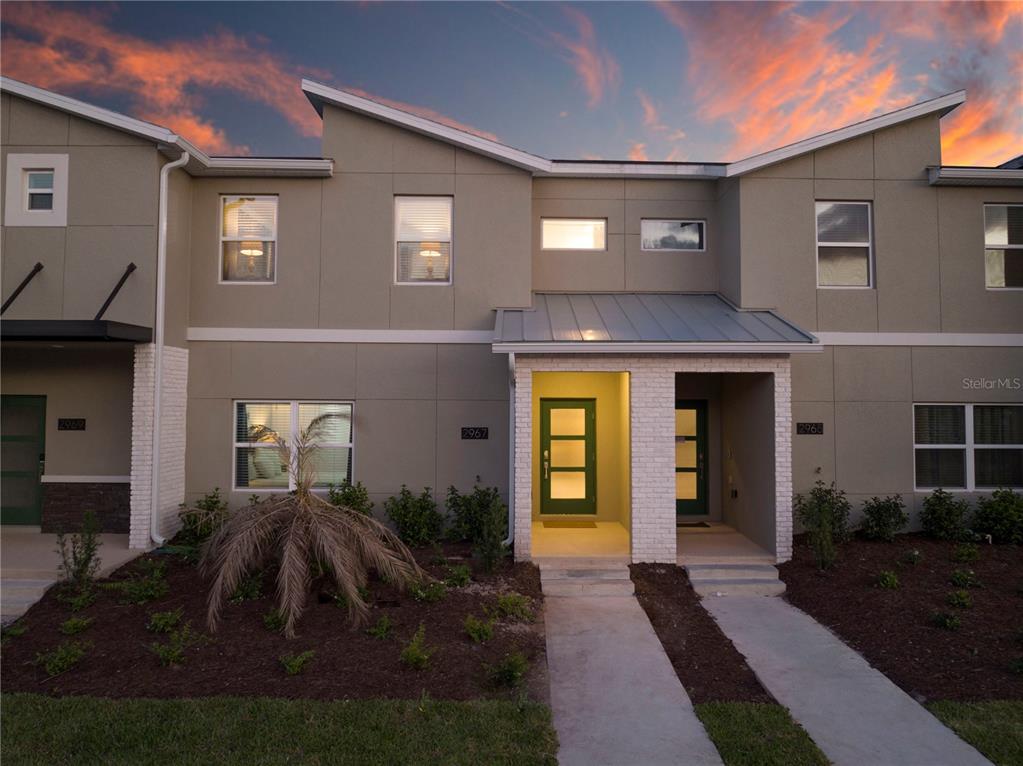 A modern two-story townhouse exterior features a green front door and a metal roof awning — 2967 PENELOPE LOOP, KISSIMMEE, FL